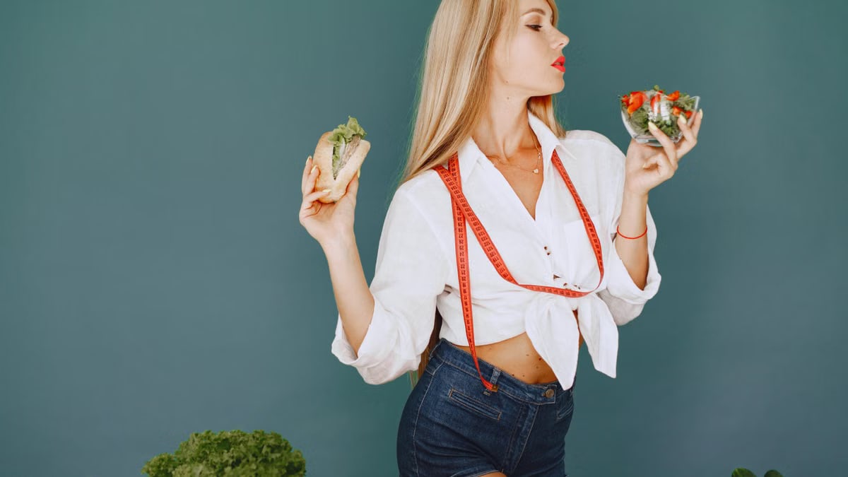 Woman enjoys healthy lifestyle with fresh salad and sandwich, promoting balanced eating.